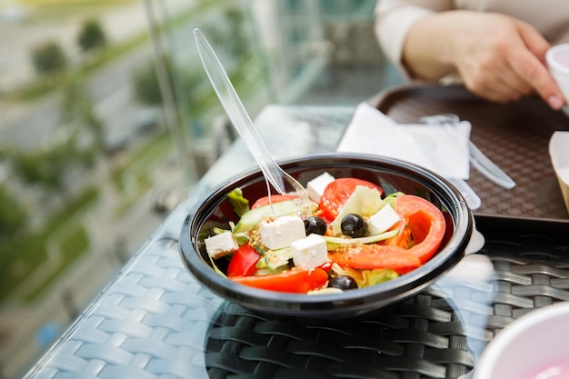 Das Mädchen im Café isst zu Abend griechischen Salat auf einem Teller