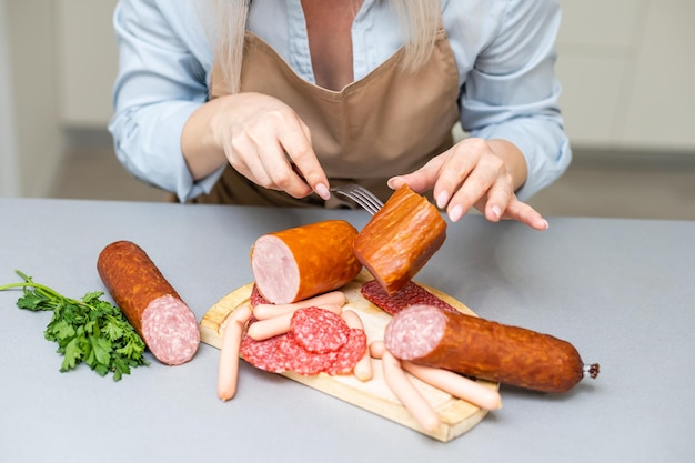 Das Mädchen isst Wurst. Ein Stück Wurst. Lächeln und Freude. Das Geschäftskonzept ist der Reiz der Marke. Appetit