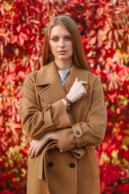 Das Mädchen ist ein Model, das modische Kleidung auf der Straße zeigt. Der Rücken des Mädchens ist ein lebender Zaun Showroom