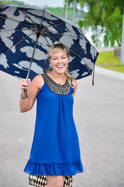 Foto das mädchen lächelt glücklich und versteckt sich hinter einem regenschirm