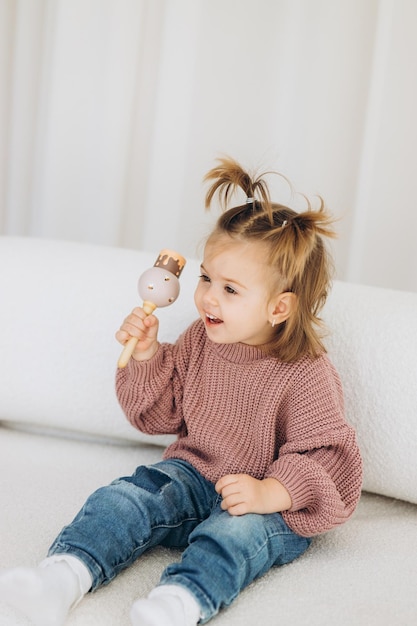 Foto das mädchen lernt farben, indem es mit farbigen menschlichen holzfiguren spielt und sie in becher der entsprechenden farbe legt. das kind ist glücklich, dass es die aufgabe richtig erledigt hat