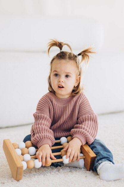 Das Mädchen lernt Farben, indem es mit farbigen menschlichen Holzfiguren spielt und sie in Becher der entsprechenden Farbe legt. Das Kind ist glücklich, dass es die Aufgabe richtig erledigt hat