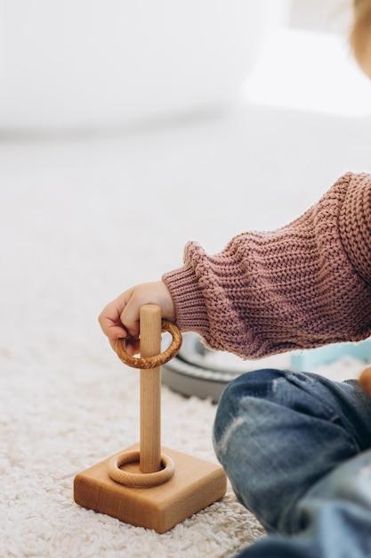 Foto das mädchen lernt farben, indem es mit farbigen menschlichen holzfiguren spielt und sie in becher der entsprechenden farbe legt. das kind ist glücklich, dass es die aufgabe richtig erledigt hat