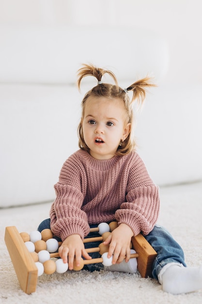 Foto das mädchen lernt farben, indem es mit farbigen menschlichen holzfiguren spielt und sie in becher der entsprechenden farbe legt. das kind ist glücklich, dass es die aufgabe richtig erledigt hat