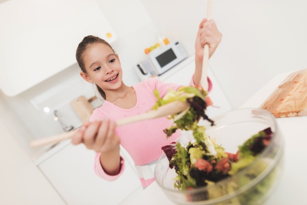 Das Mädchen lernt, in einer hellen Küche einen Salat zuzubereiten.