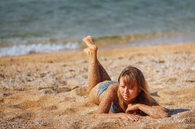 Das Mädchen liegt am Strand. Großer blauer Seehintergrund