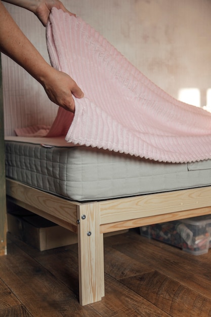 das Mädchen macht das Bett mit einer Decke