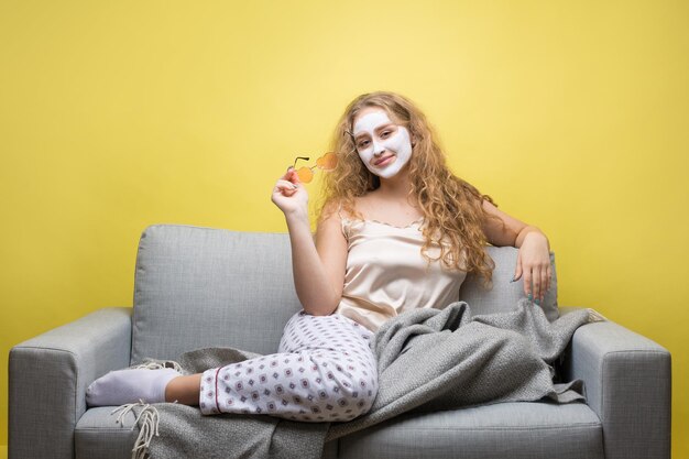 Das Mädchen macht Verfahren mit einer kosmetischen Maske im Gesicht.