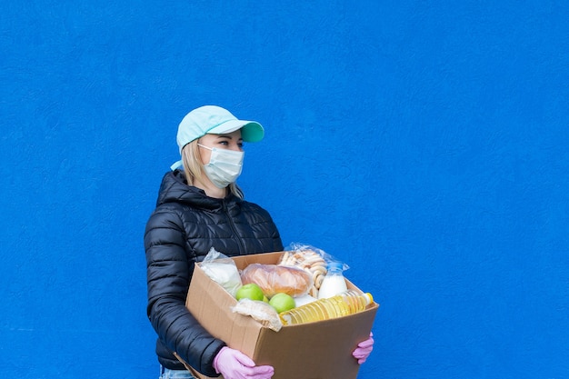 Das Mädchen meldet sich freiwillig mit Wohltätigkeitsbox auf blauem Hintergrund