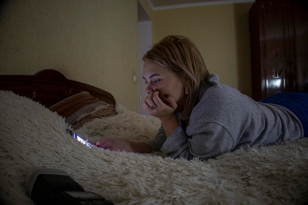 Das Mädchen mit dem Telefon liegt auf dem Bett