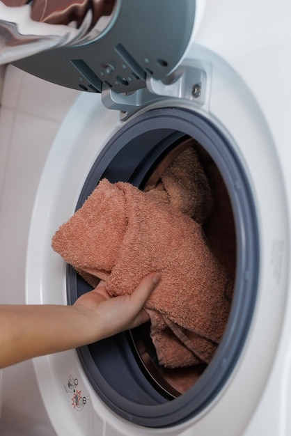 Foto das mädchen nimmt die gewaschenen sachen aus der waschmaschine mädchenhände falten dinge beim waschen