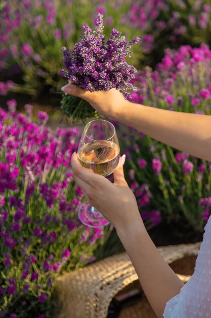 Das Mädchen ruht sich in einem Lavendelfeld aus und trinkt Wein Selektiver Fokus