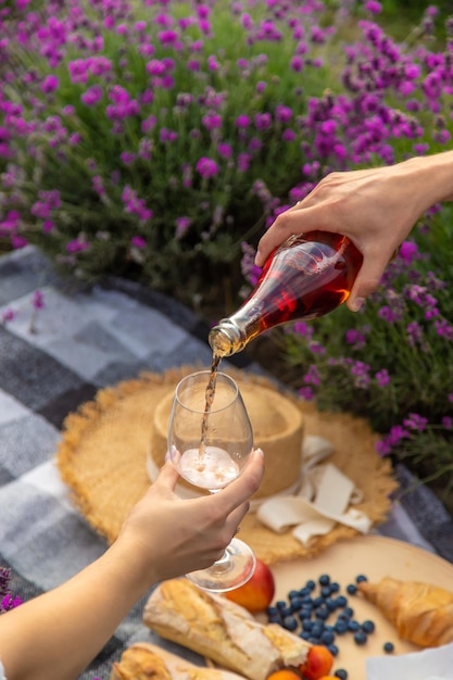 Das Mädchen ruht sich in einem Lavendelfeld aus und trinkt Wein Selektiver Fokus