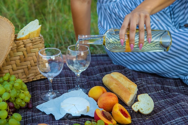 Das Mädchen schenkt Wein bei einem Picknick ein. Selektiver Fokus. Natur.