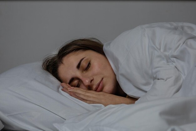 Das Mädchen schläft in einem Bett mit einem weißen Laken