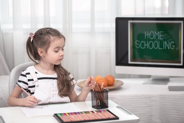 Das Mädchen sitzt am Tisch und macht Hausaufgaben. Das Kind lernt zu Hause. Heimschul- und Bildungskonzept.