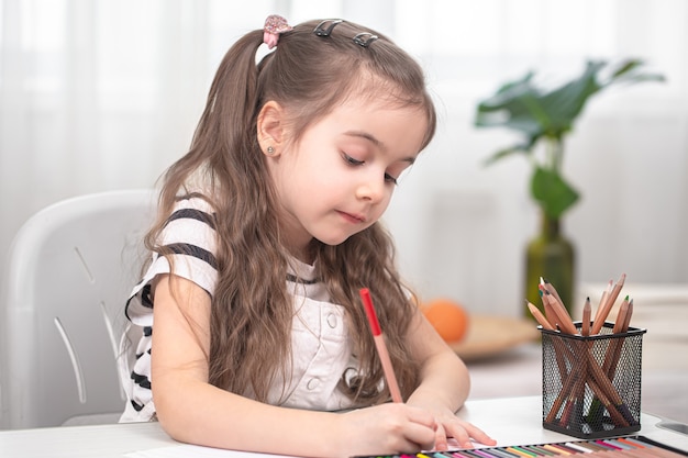 Das Mädchen sitzt am Tisch und macht Hausaufgaben. Das Kind lernt zu Hause. Heimschulkonzept.