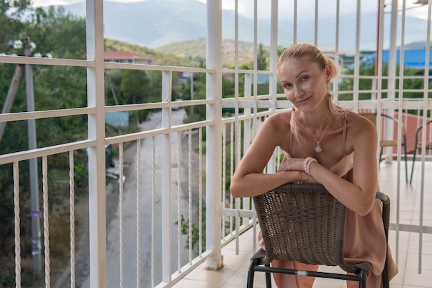 Das Mädchen sitzt auf dem Balkon der Berge und des blauen Himmels auf dem Hintergrund der Schönheit