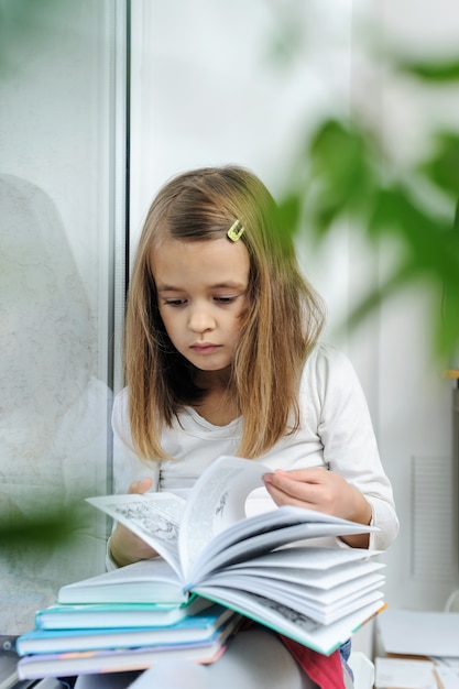 Das Mädchen sitzt auf der Fensterbank und liest ein Buch.