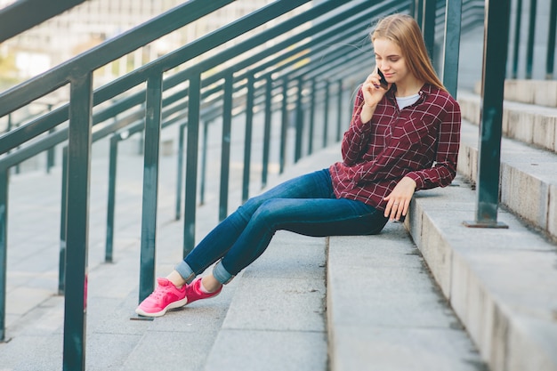 Das Mädchen sitzt auf der Treppe und telefoniert