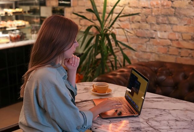 Das Mädchen sitzt in der Cafeteria am Laptop