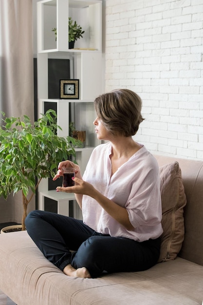 Das Mädchen sitzt mit einer Tasse Tee auf der Couch Das Mädchen ruht sich zu Hause aus