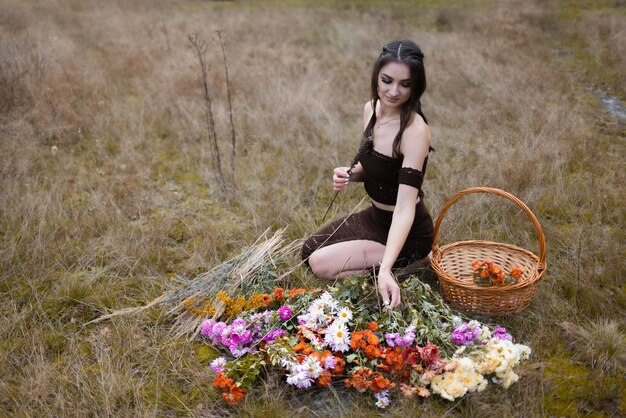 Das Mädchen sitzt neben vielen Blumen auf dem Feld