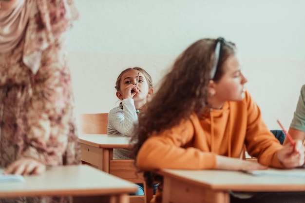 Foto das mädchen sitzt verwirrt mit den händen auf dem kopf auf der schulbank und besucht den unterricht selektiver fokus foto in hoher qualität