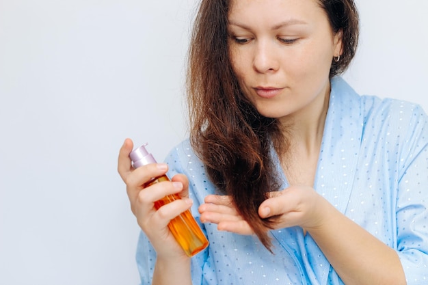 Das Mädchen trägt kosmetisches Öl auf die flauschigen Haarspitzen auf