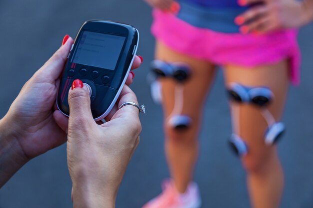 Das Mädchen trainiert mit einem Elektrostimulator. Übungen und Belastung der Beinmuskulatur mit einem Elektrostimulator.