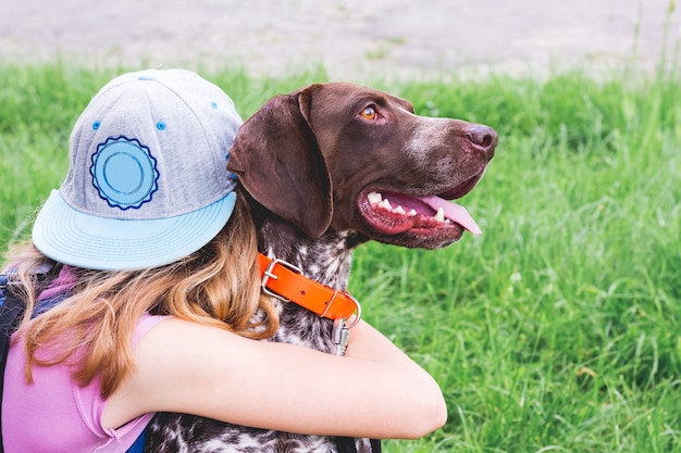 Foto das mädchen umarmt einen hund der rasse deutsch kurzhaar. das kind und der hund sind freunde