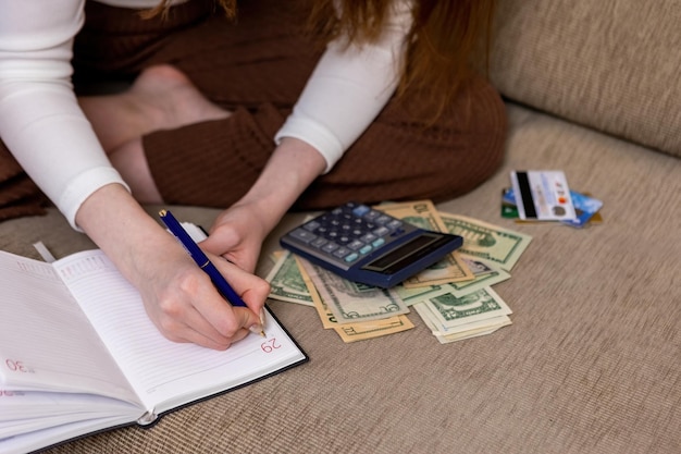 Das Mädchen zählt das Budget auf einem Taschenrechner und schreibt es in ein Notizbuch