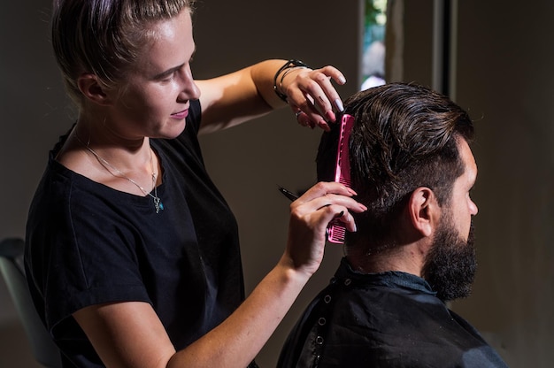 Das männchen ist ein dunkelhaariger kaukasier auf einem haarschnitt in einem friseursalon