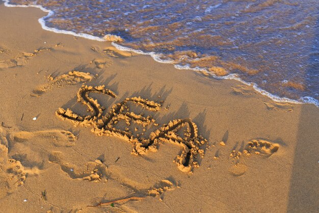 Das Meer ist auf nassem Sand am Strand mit Wellen geschrieben