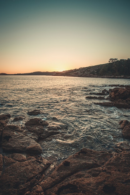 Das Meer kracht während eines Sonnenuntergangs gegen die Felsen an der Küste