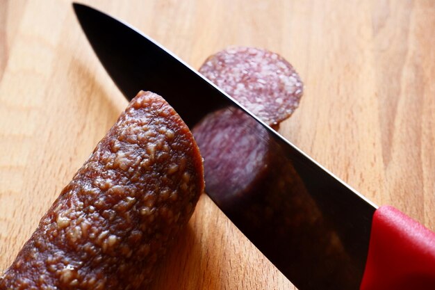 Foto das messer schneidet salami auf einem holzbrett