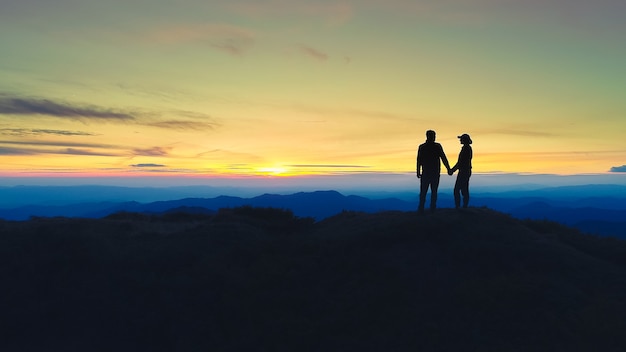 Das Paar, das auf dem Berg auf dem Sonnenaufganghintergrund steht