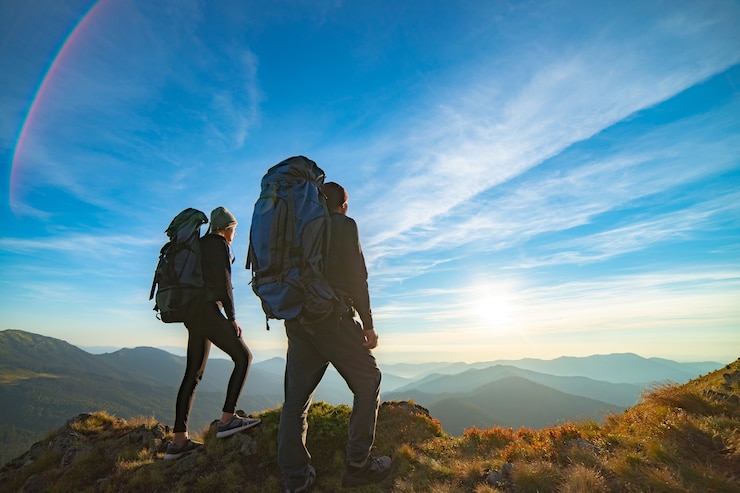Foto das paar, das auf dem berg mit einem malerischen sonnenaufganghintergrund steht