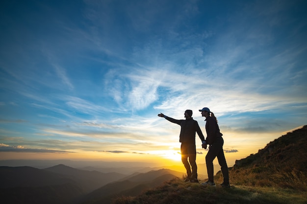 Das Paar gestikuliert auf den Felsen mit einem malerischen Sonnenaufgang