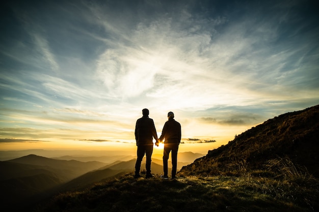 Das Paar steht auf dem Felsen mit einem malerischen Sonnenaufgang