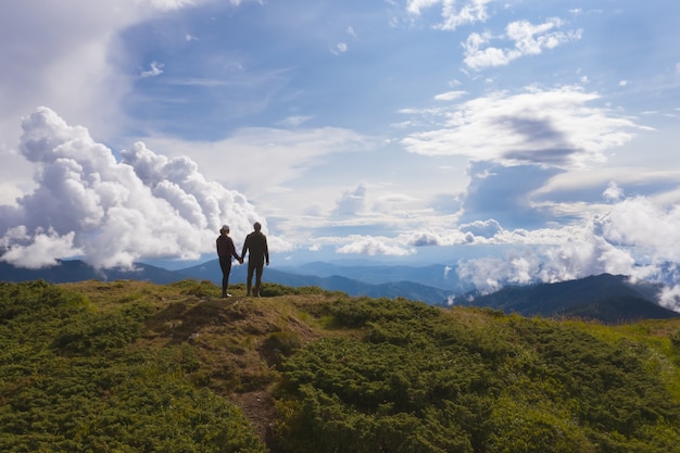 Das Paar steht auf einem Berg gegen schöne Wolken