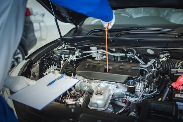 Das Personal des Automechanikers zieht die Ölstandsanzeige nach oben, um den Ölstand zu prüfen. Um den Zustand des Autos zu überprüfen