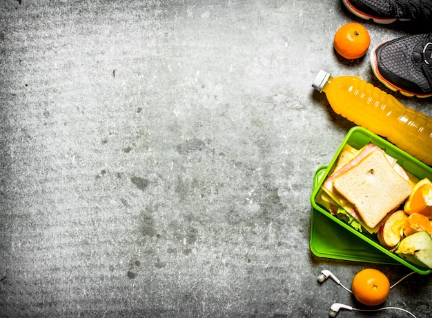 Das Picknick stellte Sandwiches, Orangensaft und Obst auf den Steintisch