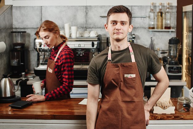 Das Porträt der Baristas am Arbeitsplatz auf dem Hintergrund des Kaffees