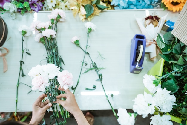 Das Porträt des Floristen der Hand macht ein Blumenhandwerk auf dem Tisch