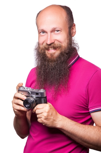 Das Porträt des glatzköpfigen bärtigen Mannfotografen mit rosa T-Shirt mit klassischer Kamera. isoliert auf weißem Hintergrund. Studioaufnahme.