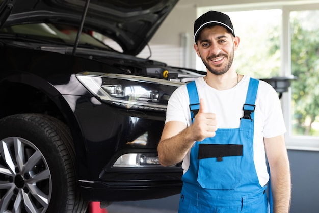 Das Porträt eines bärtigen Automechanikers in einer Autowerkstatt zeigt einen positiven Autoservice-Mitarbeiter mit Daumen nach oben