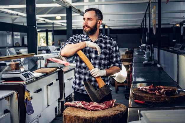 Das Porträt eines bärtigen Fleischmannes in einem Fleecehemd hält eine Axt und frisch geschnittenes Fleisch.