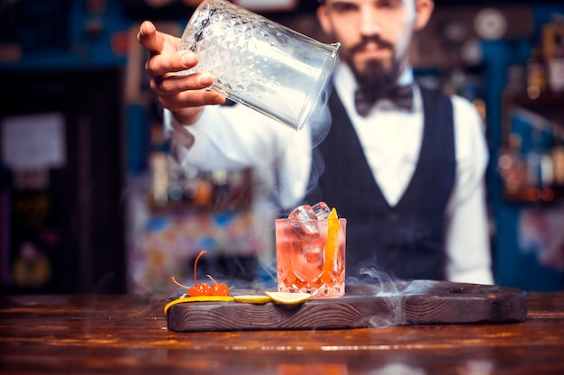 Das Porträt eines Barmanns gießt an der Bar einen Drink ein