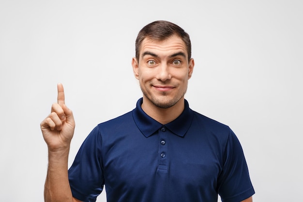 Das Porträt eines dunkelhaarigen Mannes im blauen T-Shirt zeigt den Finger auf weißem Hintergrund